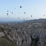 Dozens of hot air balloons drifting over the eroded valleys near Göreme in Cappadocia at dawn