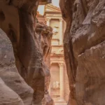 The Treasury at Petra framed by the dark walls of the Siq at the end of the gorge