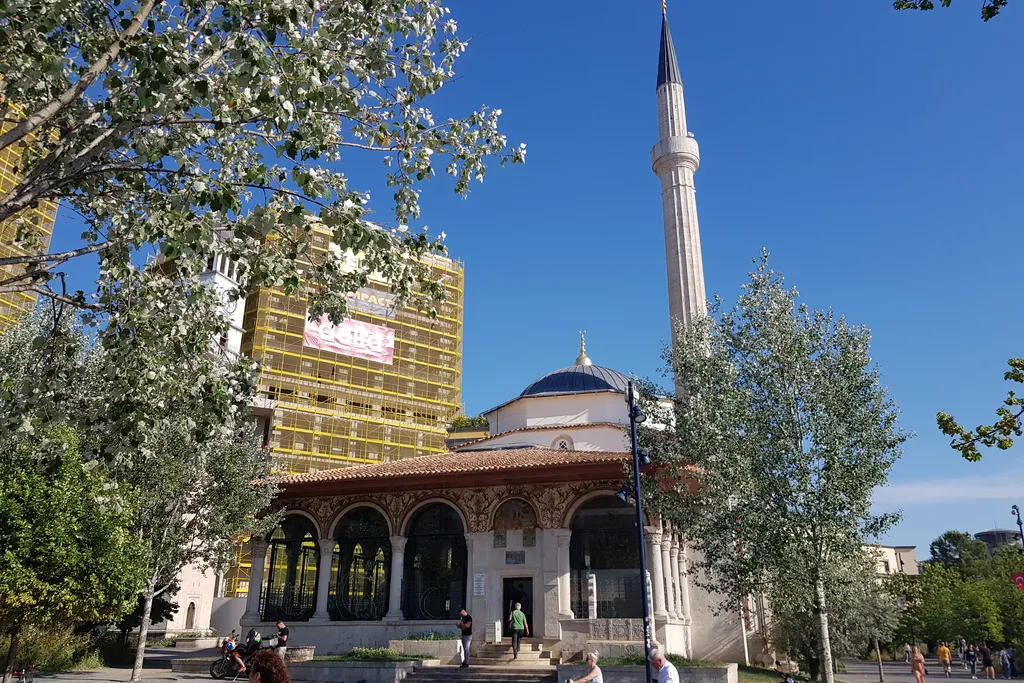 The Et'hem Bey Mosque on Skanderbeg Square in Tirana, its painted portico and minaret against a blue sky